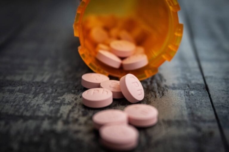 A table displaying a glass of alcohol next to several pills, evoking themes of substance use and caution.